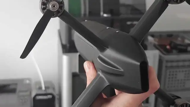 Black drone airframe held in hand in a workshop
